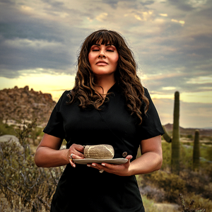 Cecilia Berkley holding a plate with a desert landscape and cactus in the background